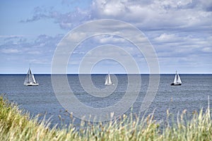 Three yachts in a line on the sea at the coast