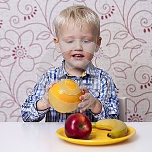 The three-year boy eats a yellow grapefruit