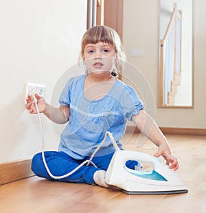 Three year old baby playing with iron