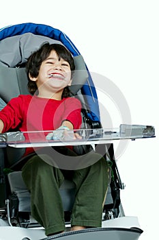 Three year old biracial disabled boy in medical stroller, happy