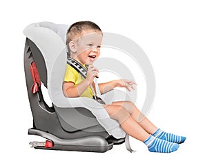 Three-year-old boy sits in an automobile children`s chair