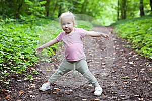 Three-year-old Caucasian girl runs and plays in the park on a path