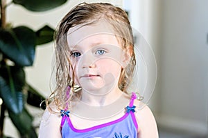 A three year old girl looking at the camera posing after bath time with wet hair,