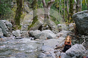 three year old girl playing with an old doll near a river in the beautiful nature of the Dirfi mountain in Eubeoa