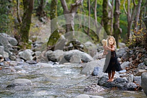 three year old girl playing with an old doll near a river in the beautiful nature of the Dirfi mountain in Eubeoa photo