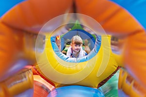 A three-year-old girl plays on a children`s inflatable trampoline in an amusement park. A small child on the playground. An Active