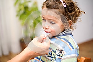 A three-year-old girl spits into a saliva test tube for covid19 antigens