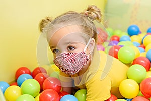 Three year old girl wearing face mask during playing at her occupational child therapy session. Covid-19 epidemic concept.