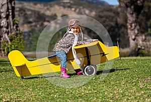 Three-year-old girl on yellow toy airplane outdoors