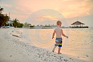 Three year old toddler boy on beach at sunset