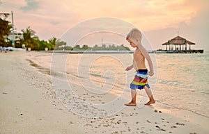 Three year old toddler boy on beach at sunset