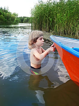 Three years old boy and a boat in a water
