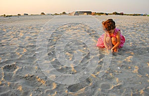 Three years old girl playing with sand on the beach