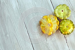 Three yellow and green bush pumpkins on white wood background. Garden,agriculture and farming concept.