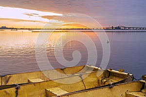 Three yellow metal boats tied together on calm lake at dawn under a brilliant gold and violet sunrise