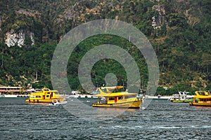 Three yellow passenger tourist speed boat, cruising near beach. Sea taxi