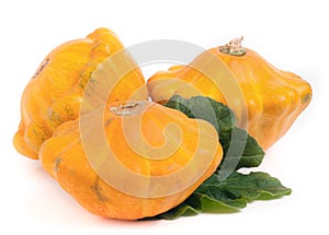 Three yellow pattypan squash with leaf isolated on white background