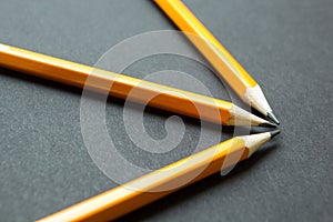 Three yellow pencils on a black background, concept