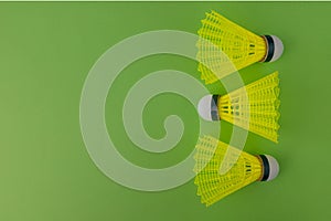 Three yellow shuttlecocks on a green background with copy space
