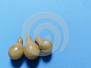 Three yellow tomatoes and blue background
