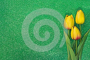 Three yellow tulips on green background with sparkles. Greeting card with Easter, March 8, happy birthday, mother`s day