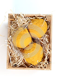 Three yellow yuzu citrus fruits in a wooden box with shavings photo