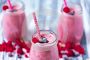 Three yogurt smoothie with cranberry, raspberry, blueberry on wood table in jars. Selective focus