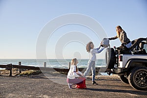 Three young adult girlfriends unloading backpacks from a car
