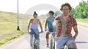 Three young adults having fun cycling and taking selfies, graded