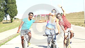 Three young adults having fun cycling and taking selfies, graded