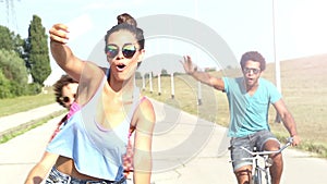 Three young adults having fun cycling and taking selfies, graded