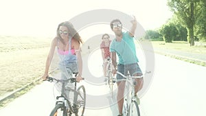 Three young adults having fun cycling and taking selfies, graded