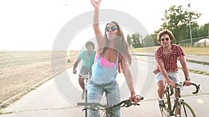 Three young adults having fun cycling and taking selfies, graded