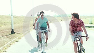 Three young adults having fun cycling and taking selfies, graded