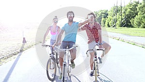 Three young adults having fun cycling and taking selfies, graded
