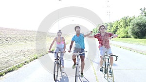Three young adults having fun cycling and taking selfies, graded