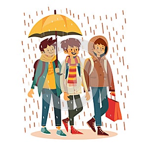 Three young adults walking under yellow umbrella during rain. Friends enjoying stroll despite photo