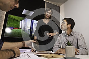 Three young architects discussing together inside a conference room the new interior design concept for a brand presentation.