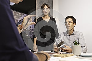 Three young architects discussing together inside a conference room the new interior design concept for a brand presentation.