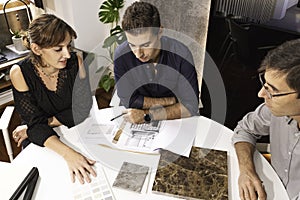 Three young architects discussing together inside a conference room the new interior design concept for a brand presentation.