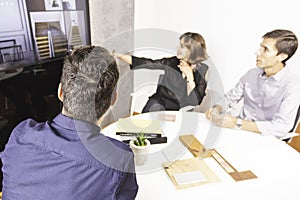 Three young architects discussing together inside a conference room the new interior design concept for a brand presentation.