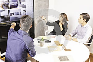 Three young architects discussing together inside a conference room the new interior design concept for a brand presentation.