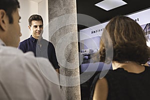 Three young architects discussing together inside a conference room the new interior design concept for a brand presentation.