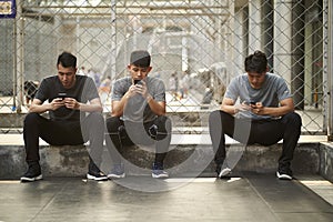 Three young asian adult men looking a cellphone