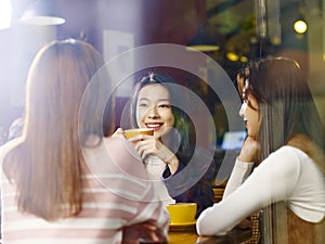 Three young asian women chatting talking in coffee shop