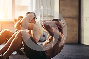 Group of athletic adult men and women performing sit up exercises