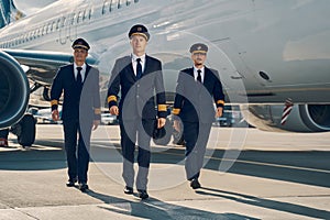 Three young aviators walking across the aerodrome