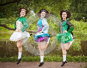 Three young beautiful girls in irish dance dress and wig dancing