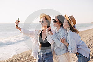 Three young beautiful happy women female friends making selfie and having fun on a beach