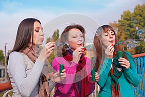 Three young beautiful women blow bubbles